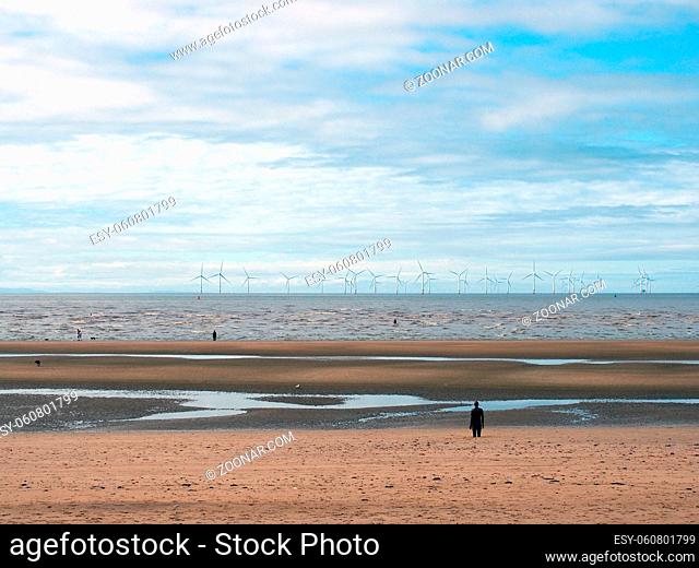 the beach at blundell flats in sefton, southport with pools on the beach the beach and the wind turbines at burbo bank visible in the distance