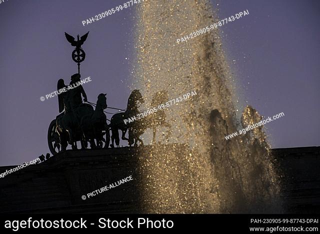 05 September 2023, Berlin: In the light of the setting sun, the Quadriga on the Brandenburg Gate can only be seen as a silhouette