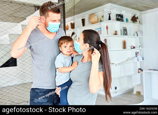Eltern mit Kind tragen Mundschutz aus Vorsicht gegen Coronavirus und Covid-19