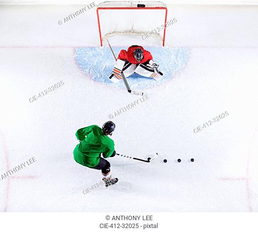 Overhead view hockey player practicing with goalie shooting puck at goal net