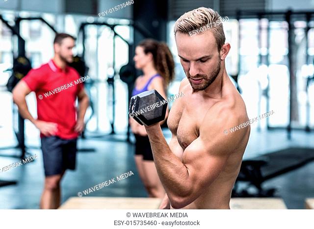 Muscular trainer lifting a dumbbell