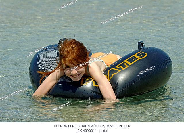Girl in a big floating tyre in the turquoise waters in the Bay of Rondinara, southeast coast, Corsica, France