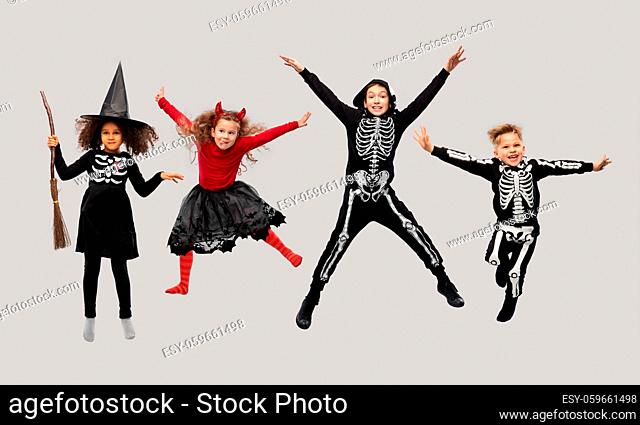 happy children in halloween costumes jumping