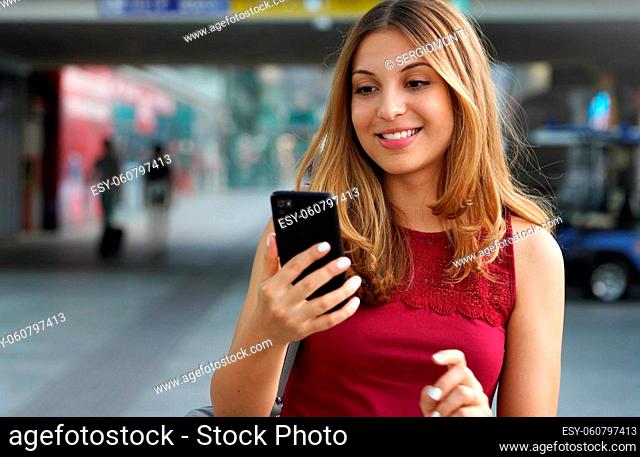 Close-up of charming beautiful business woman smile in casual style using smartphone walking in train or metro station. Copy space