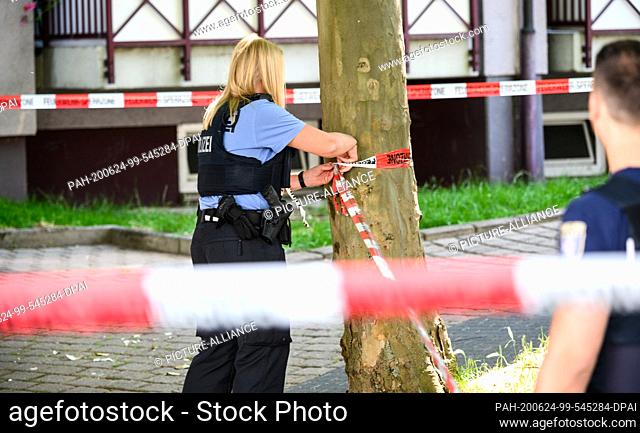 24 June 2020, Hessen, Frankfurt/Main: A policewoman is cordoning off the crime scene. A man was shot down in an underground garage in Frankfurt on Wednesday...
