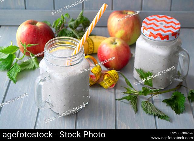Healthy organic smoothie with apples, bananas and nettle on blue table