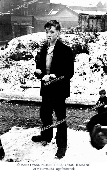 A boy stands with his hands full of snowballs in Wapping, in the East End of London. He's just working out where to throw them