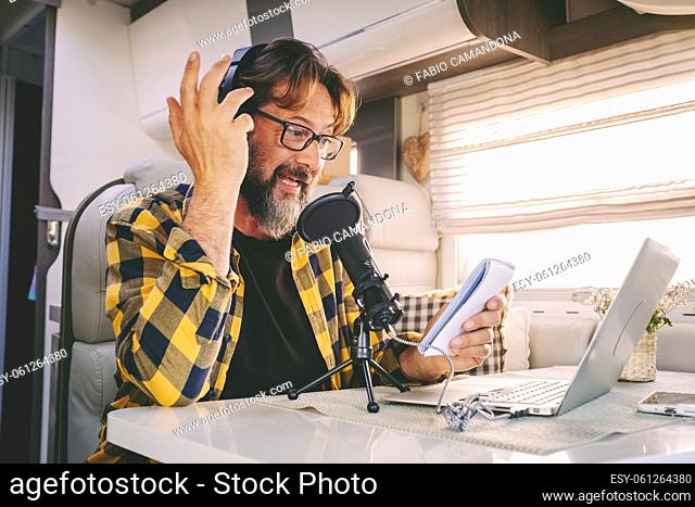One hipster man travel and work on a camper van recording voice content for a podcast. Concept of online job and smart working or digital nomad free lifestyle