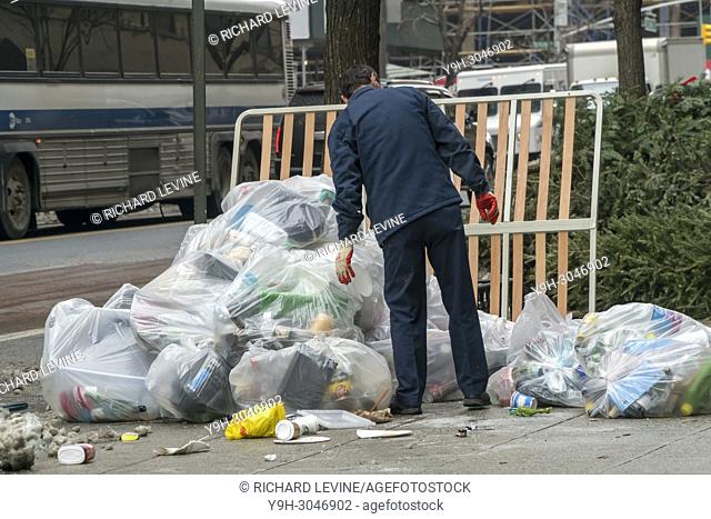 A maintenance worker deals with his building's piles of trash awaiting pick-up in New York on Thursday, January 11, 2017