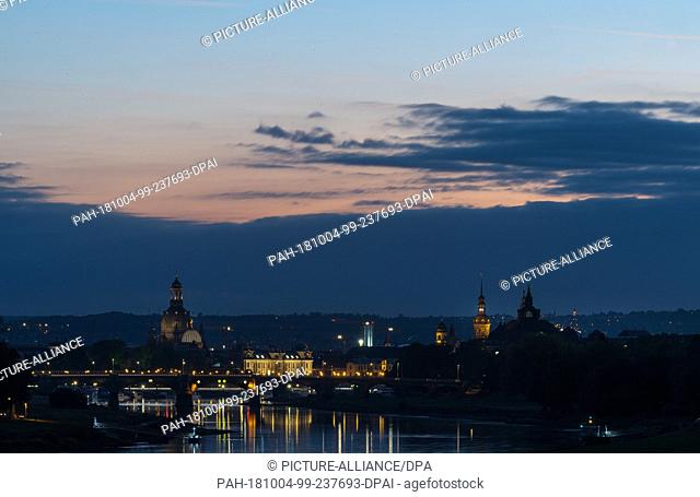 dpatop - 04 October 2018, Saxony, Dresden: Lights are reflected in the Elbe in the evening. In the background you can see the old town with the dome of the...