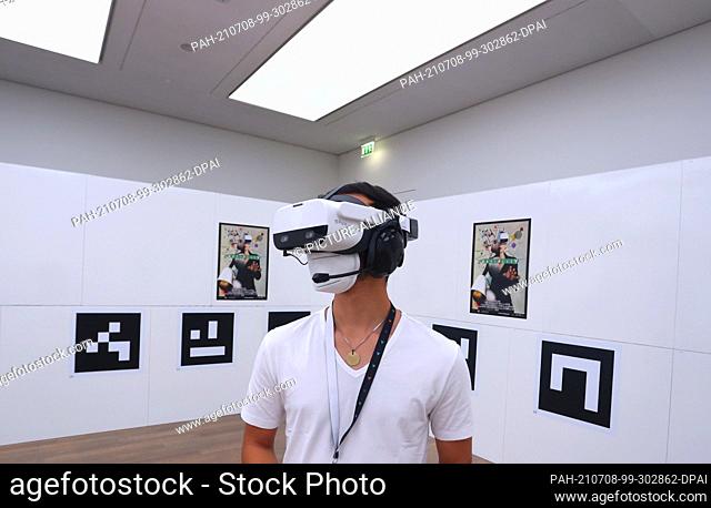 06 July 2021, Baden-Wuerttemberg, Stuttgart: A visitor to the art museum stands with virtual reality glasses on in a room in which only QR codes hang on the...