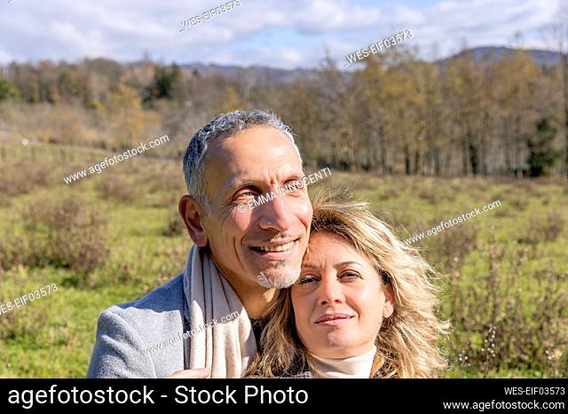 Smiling mature couple day dreaming together on sunny day