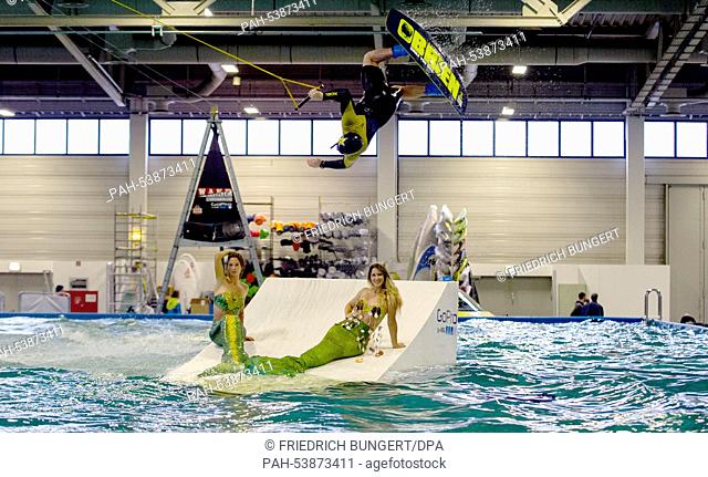 A wakeboarder jumps over a 'kicker, ' upon which two mermaids are sitting, at the 'Boat & Fun' trade fair in Berlin, Germany, 26 November 2014