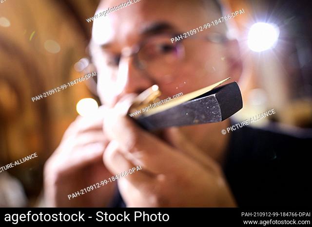 PRODUCTION - 23 August 2021, Schleswig-Holstein, Schleswig: Ekkehard Fehl, organ builder, checks a reed pipe/lingual pipe of the great organ in Schleswig...