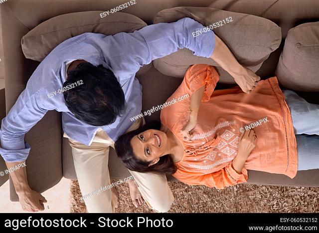 Portrait of a woman lying on her husband's lap while relaxing together on sofa