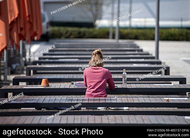 PRODUCTION - 28 April 2021, Hessen, Fulda: A student sits on the benches of the canteen at Fulda University of Applied Sciences for a video conference