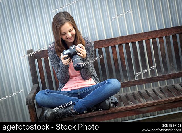 Young Girl Photographer Sitting on Bench Looking at Back of Camera