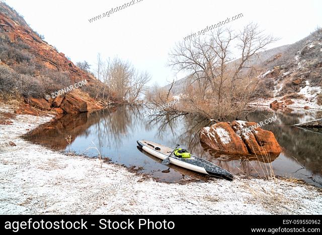 stand up paddleboard in snow blizzard on a mountain lake - Horsetooth Reservoir in northern Colorado, training, fitness and recreation concept