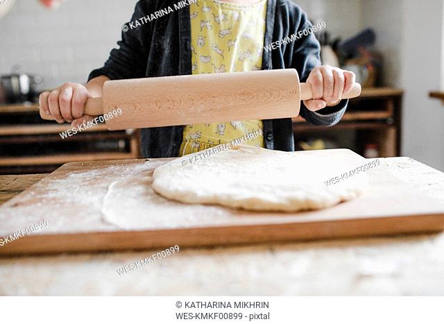 Girl's hands holding rolling pin in the kitchen, close-up