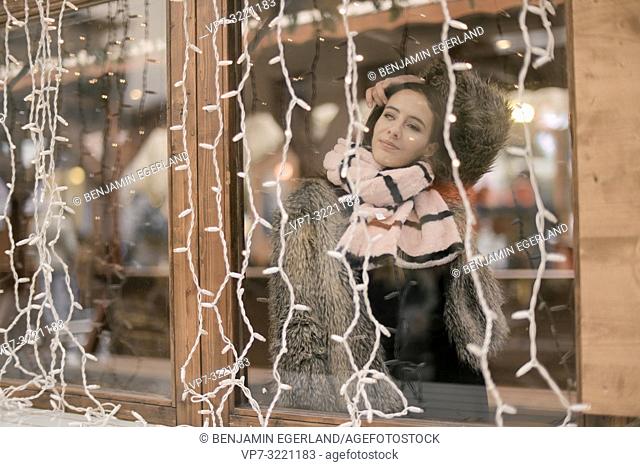 woman with winter scarf behind window, chain of lights, in Munich, Germany