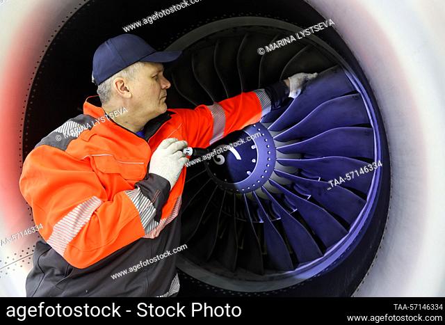 RUSSIA, MOSCOW REGION - FEBRUARY 1, 2023: An employee examines a Sukhoi Superjet 100 (SSJ100) aircraft's engine at a maintenance hangar of the Red Wings...