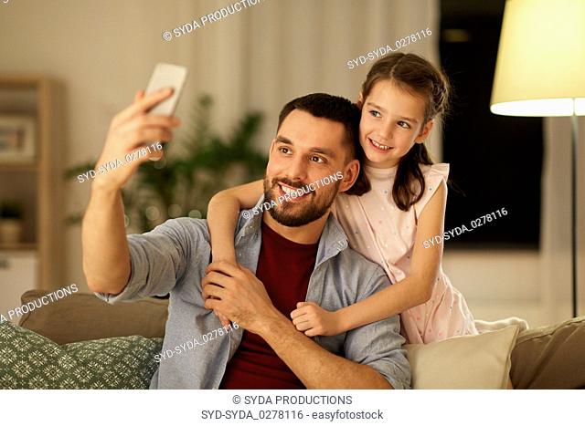 father and daughter taking selfie at home