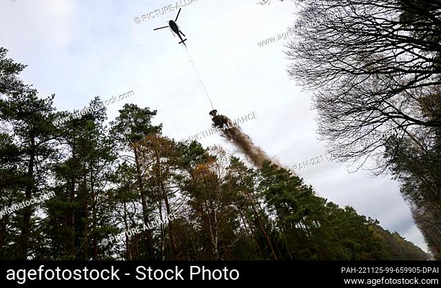 25 November 2022, Lower Saxony, Unterlüß: A helicopter is used to spread magnesium lime over a forest area. In the Lüneburg Heath, a forest area of almost 1
