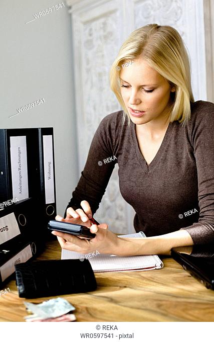 Blond woman using pocket calculator