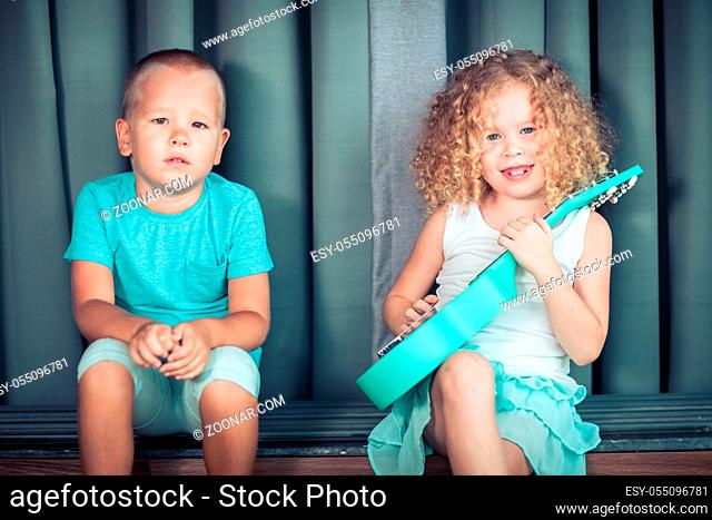 Portrait of a cute kids sitting ouddoor with ukulele