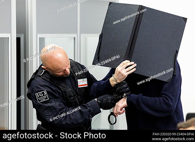 20 March 2023, Saxony, Dresden: The defendant Wissam R. (r) is led by court officials in handcuffs into the courtroom of the Dresden Higher Regional Court