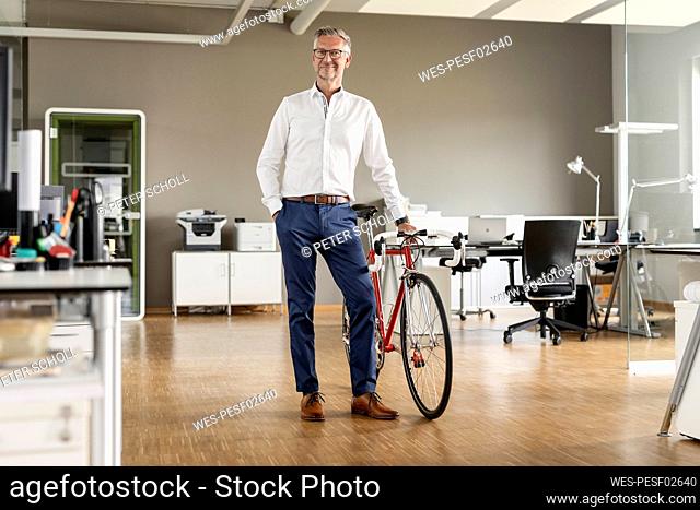 Male entrepreneur with bicycle standing in open plan office