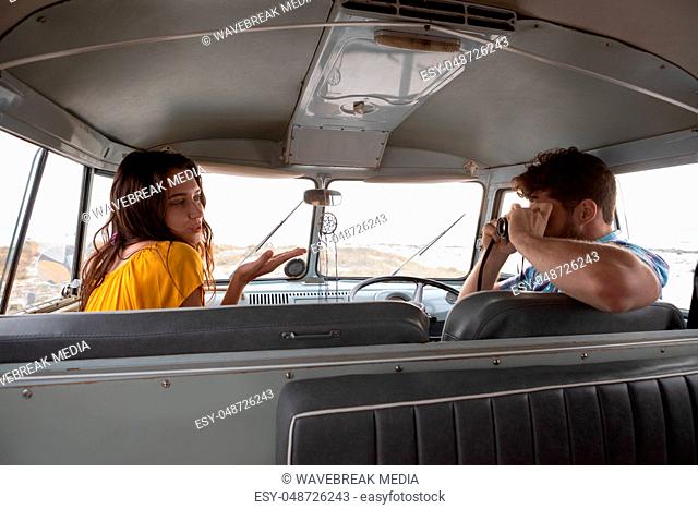Man taking photo of a woman with digital camera in camper van
