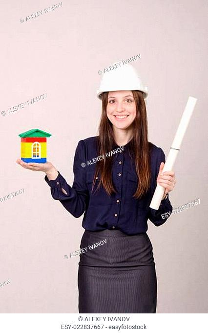 Girl stands with a house builder and drawing in hands