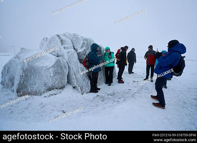 16 December 2023, Saxony-Anhalt, Schierke: Hikers walk over the Brocken in the early hours of the morning at the Brocken breakfast with geocaching and take...