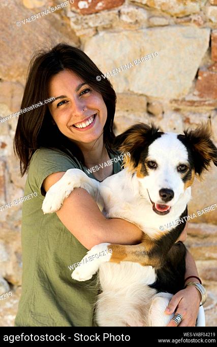 Female professional carrying pet dog against wall