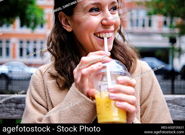 Smiling woman looking away while holding smoothie cup