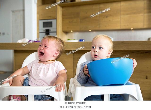 Male and female twin toddlers in high chairs