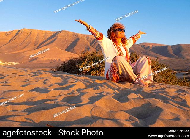 Happy people overjoyed for tourism holiday vacation. Woman sitting on the dunes sand beach outstretching arms and smile with joyful at outdoor nature around her