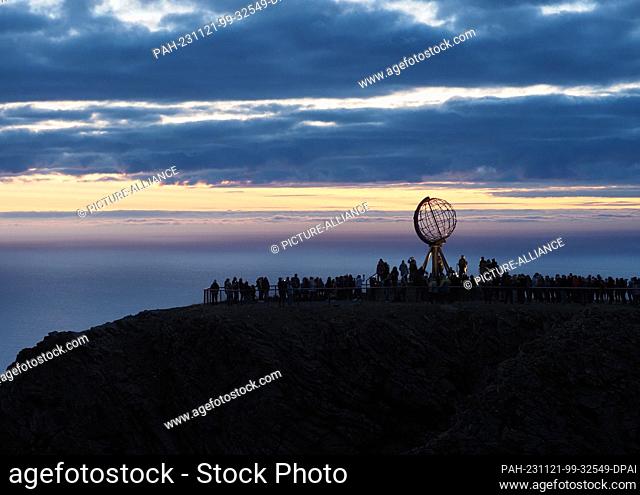 24 August 2023, Norway, Nordkapp: In the early morning, tourists visit the globe on the North Cape's slate plateau, which is located around 300 meters above the...