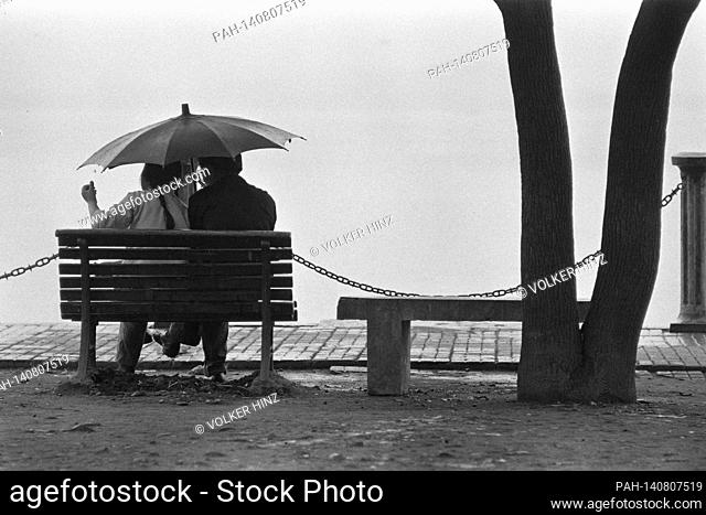 Chinese lovers sitting under an umbrella on a bench by a lake near Hangchou, 02.06.1973 | usage worldwide. - Hangchou/China