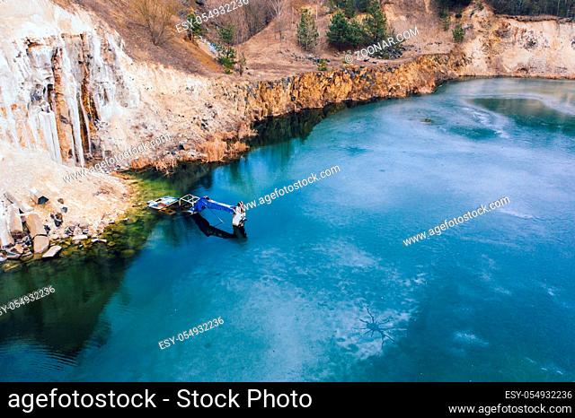 Flooded excavator in a large lake near the basaltic quarry, sunny day