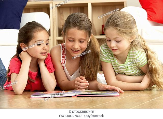 Three Young Girls Reading Book at Home