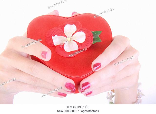 hands holding red heart-shaped box