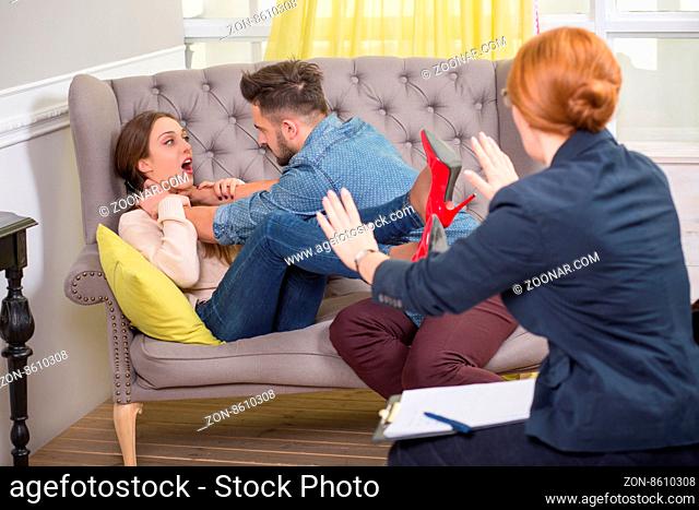 Photo of dispute married couple and relationship counseling. Psychotherapist trying to calm them down
