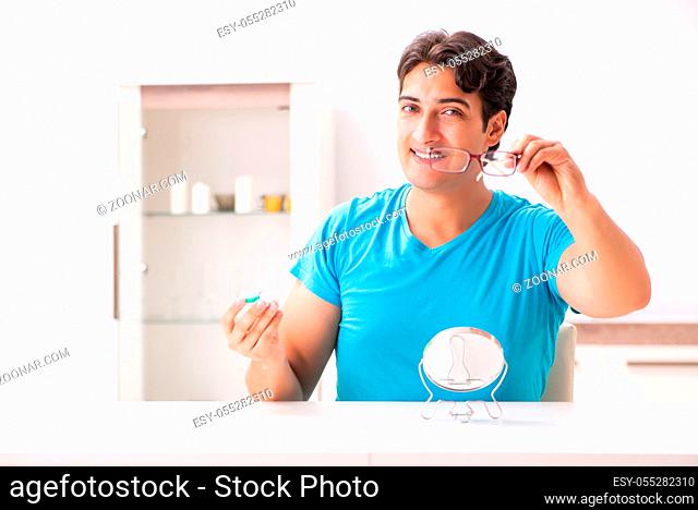 Man trying contact lenses at home