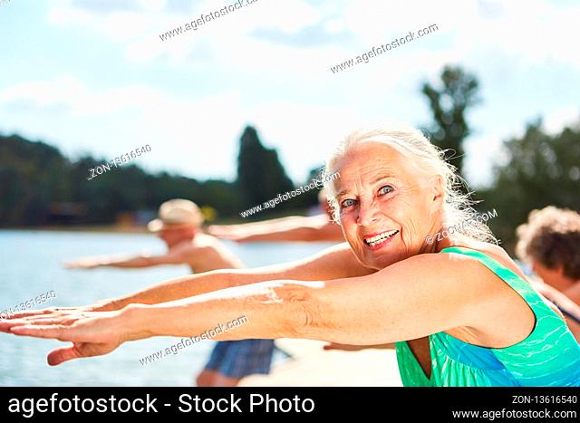 Vitale Seniorin macht Fitness Gymnastik zusammen mit Freunden im Sommer am See