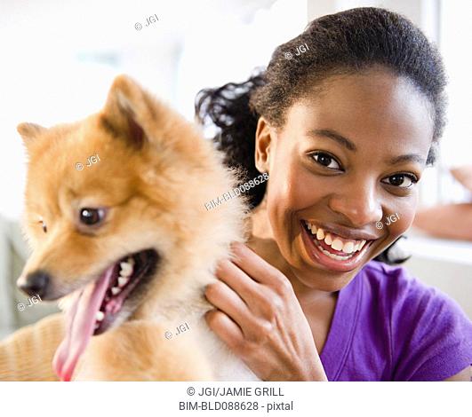Mixed race woman petting Pomeranian dog