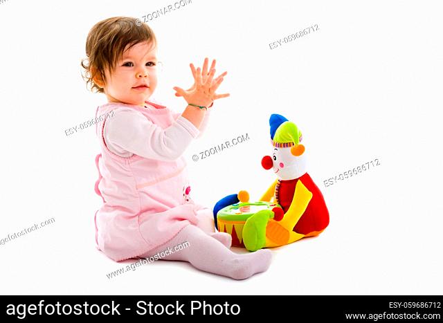 Happy baby girl sitting on floor playing with toy smiling, isolated on white background