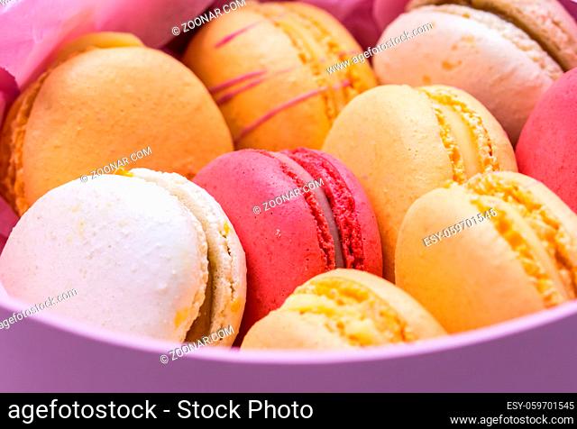 Colorful french cookies macarons set in pink gift box. Tasty fruit, almond sweet cookies, cake macaron. Holiday backdrop design