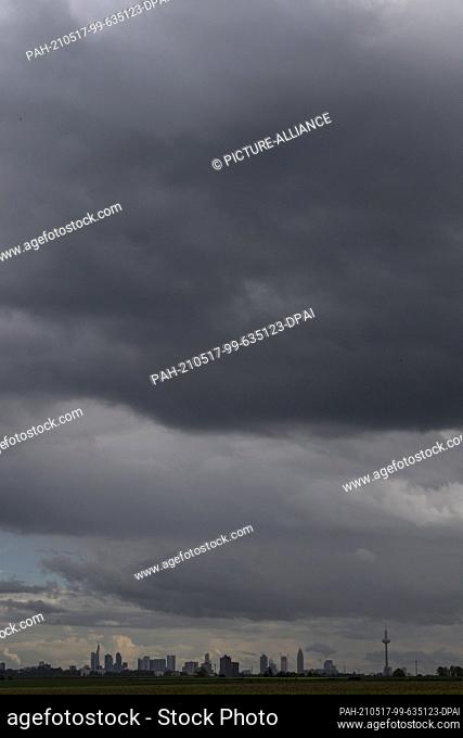 17 May 2021, Hessen, Nieder-Erlenbach: Dark storm and thunder clouds pass over the skyline of Frankfurt am Main. Photo: Boris Roessler/dpa